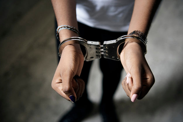 Close-up of a person's hands in metal handcuffs with bracelets, symbolizing crime and arrest