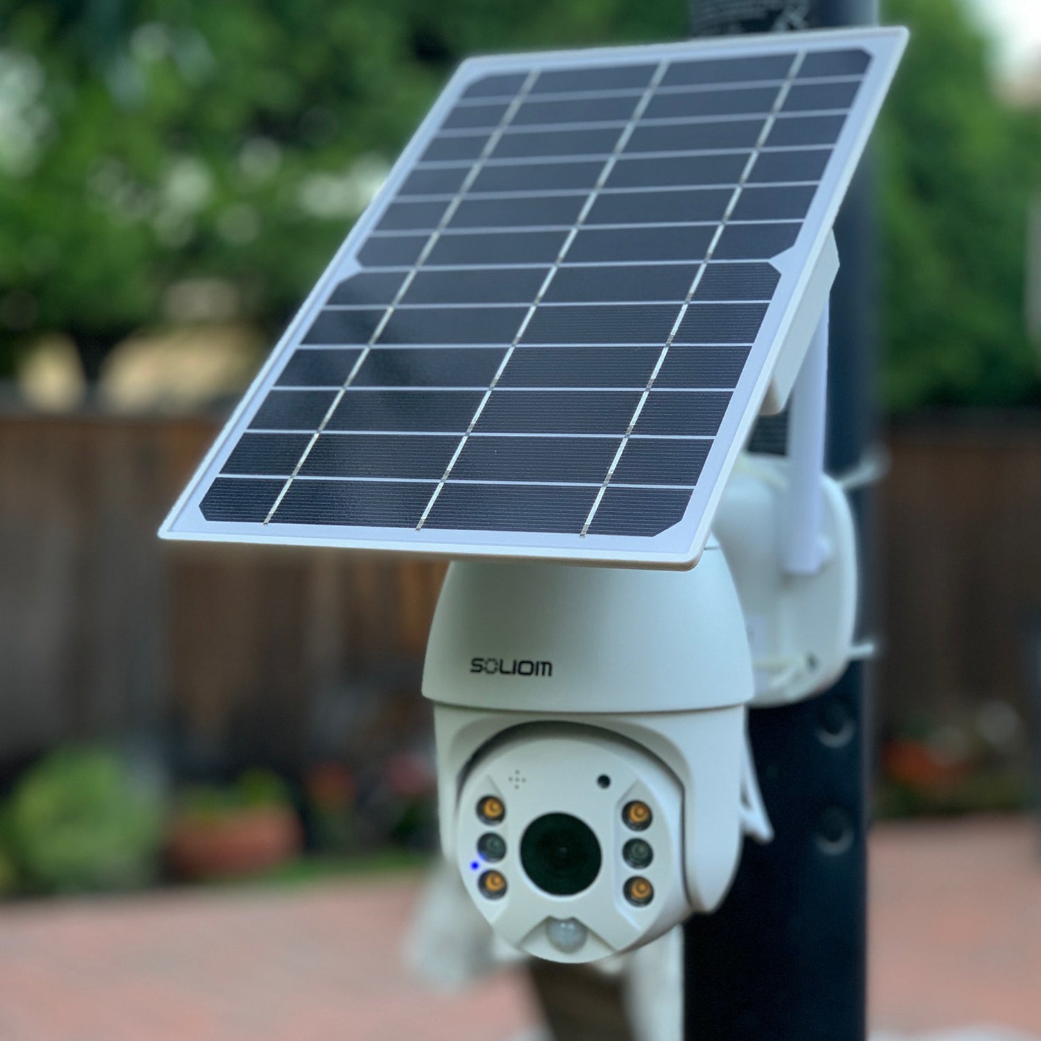 White Soliom solar-powered security camera with spotlight mounted outdoors on a pole