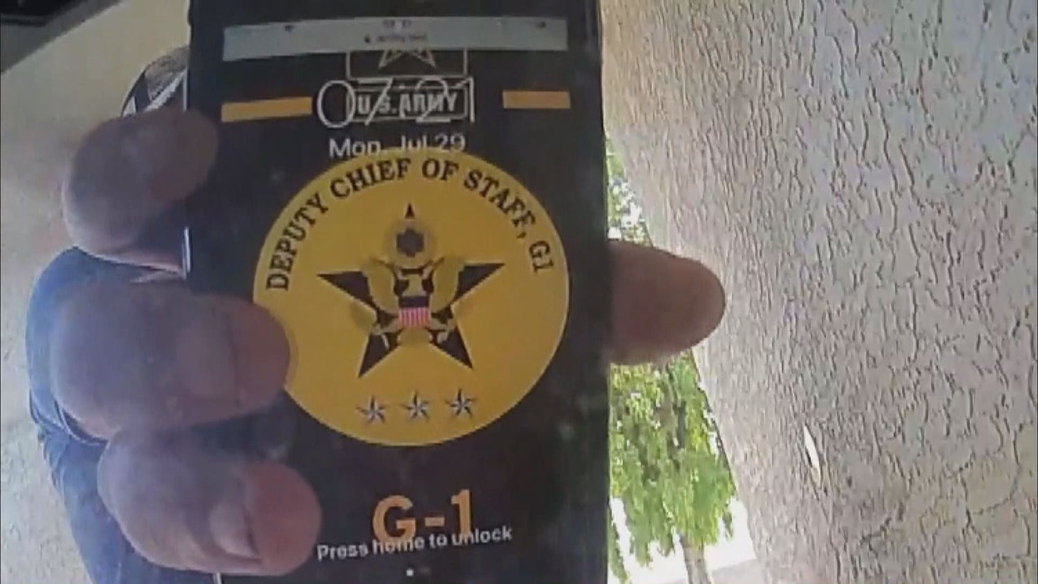 Close-up of a hand holding a smartphone displaying a U.S. Army Deputy Chief of Staff G-1 emblem on screen