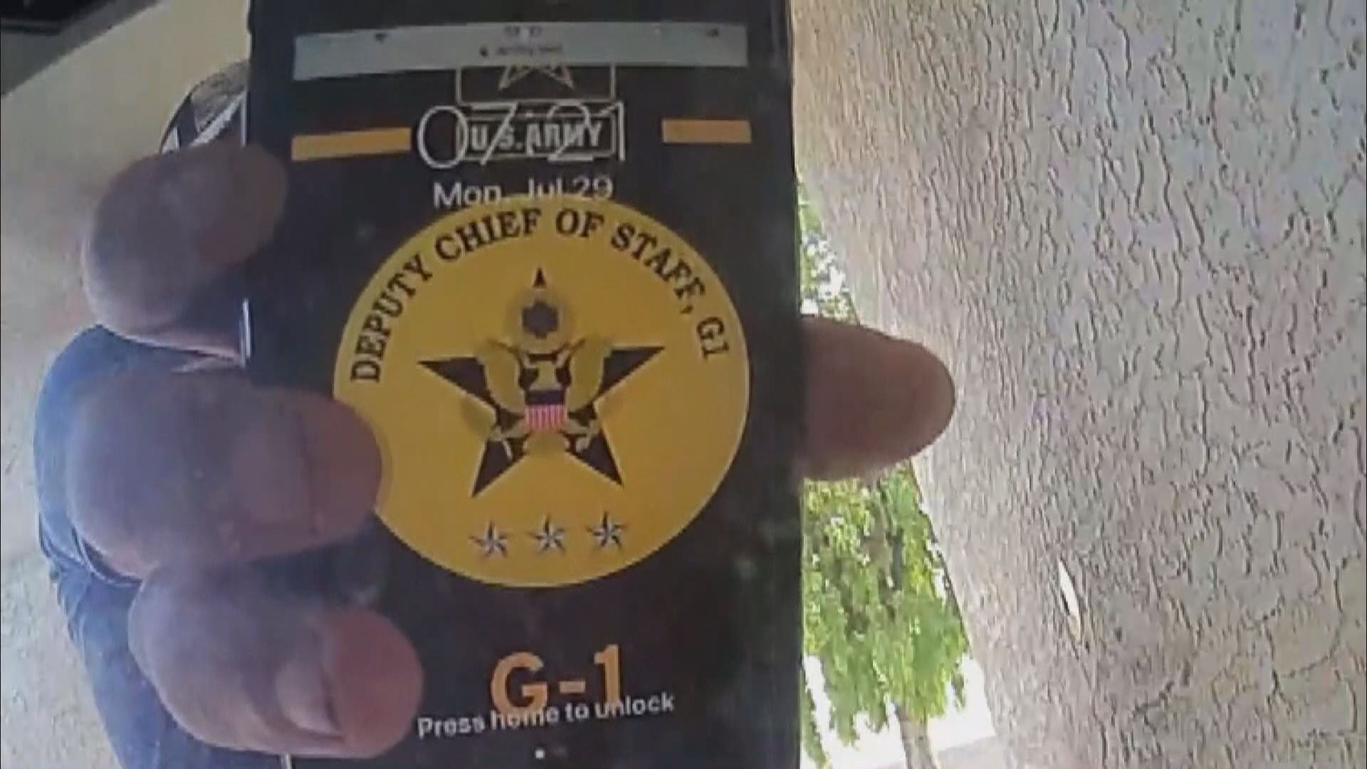 Close-up of a hand holding a smartphone displaying a U.S. Army Deputy Chief of Staff G-1 emblem on screen