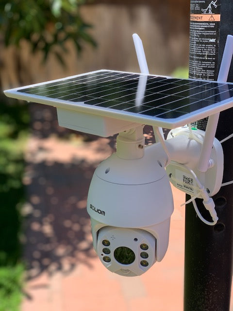 White Soliom security camera mounted on a black pole with a solar panel and dual antennas in outdoor setting