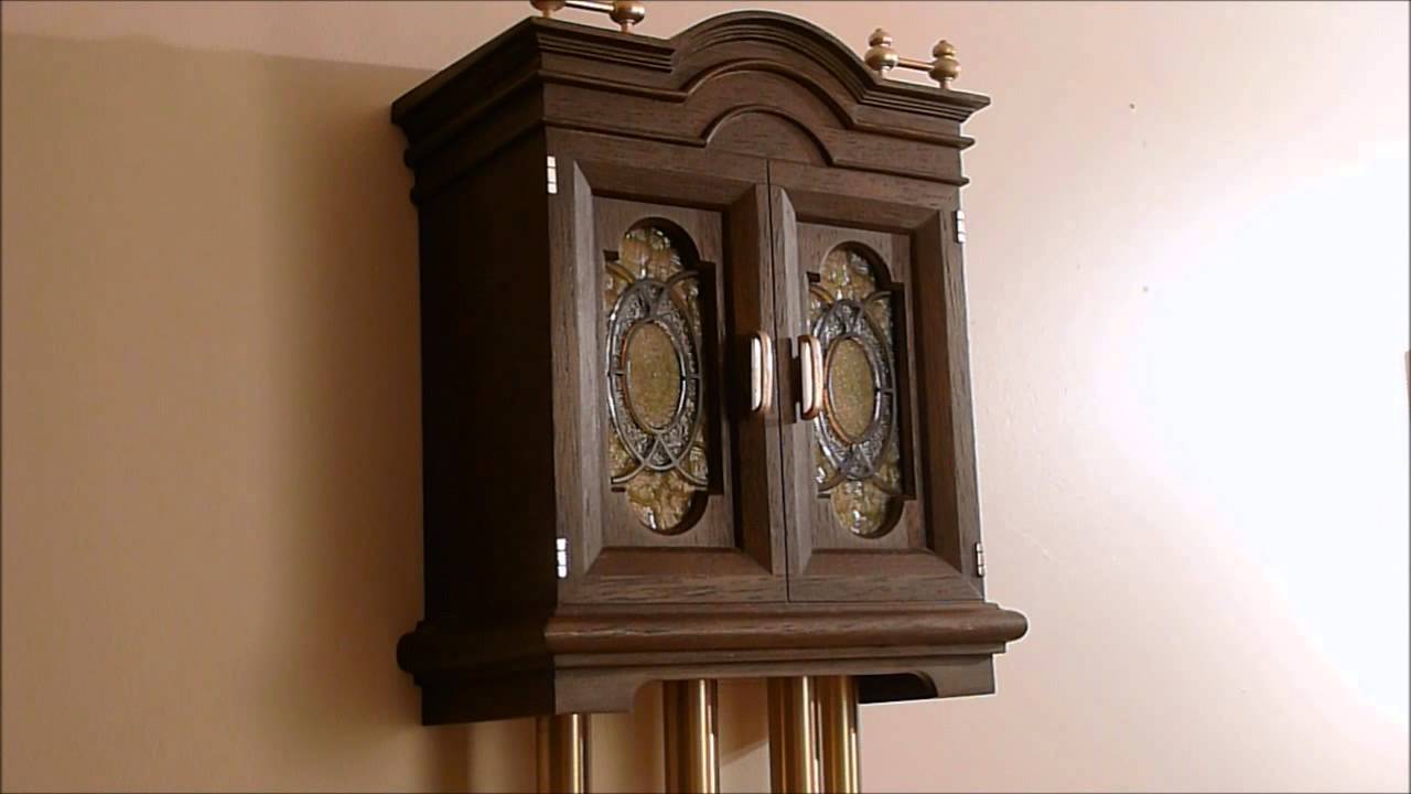 Close-up of a vintage wooden grandfather clock case with decorative glass panels and brass clock weights